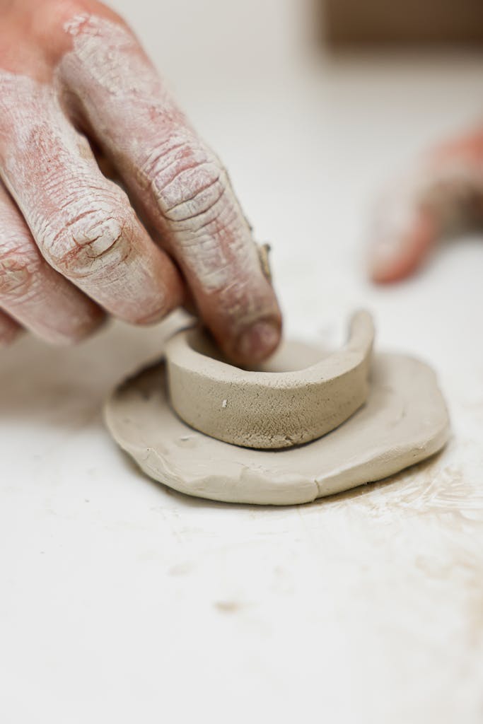 A detailed view of hands molding clay into pottery, showcasing artistic craftsmanship.